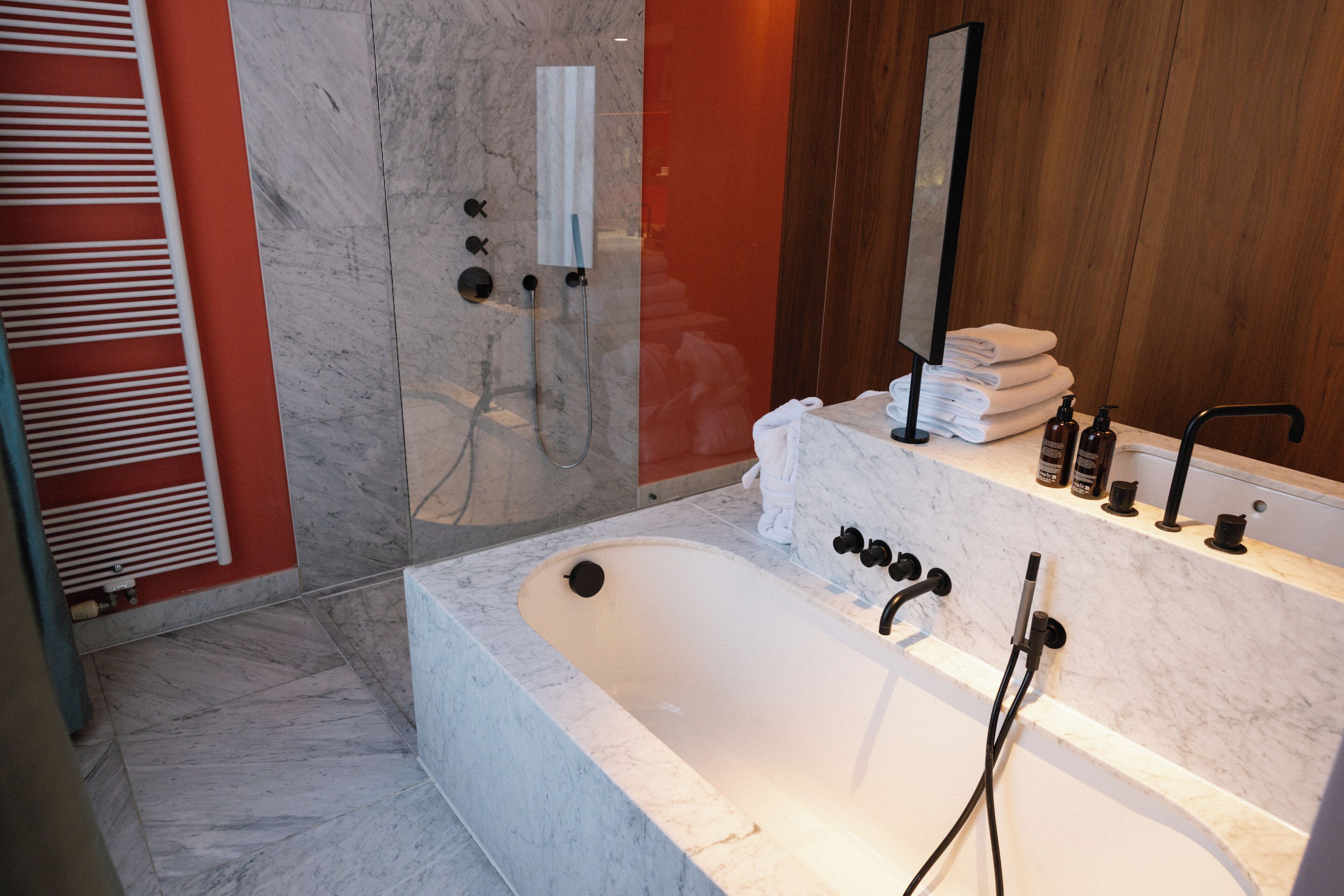 Un bagno moderno con vasca in marmo, cabina doccia in vetro e mobile lavabo in legno con articoli da toilette.