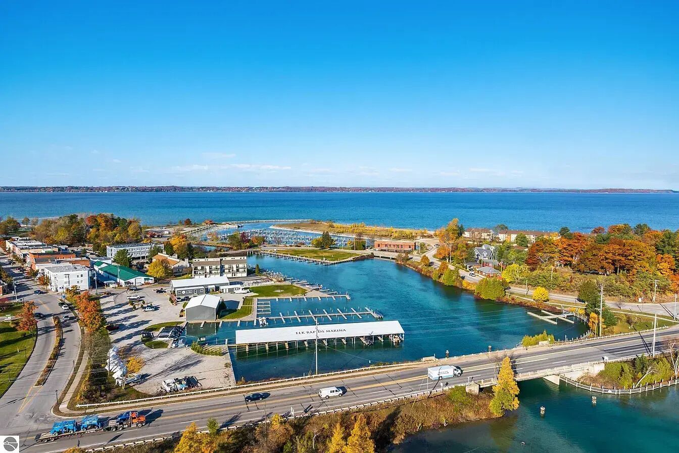 Vue aérienne d’une marina avec des zones d’amarrage, une route qui la longe et la végétation environnante.