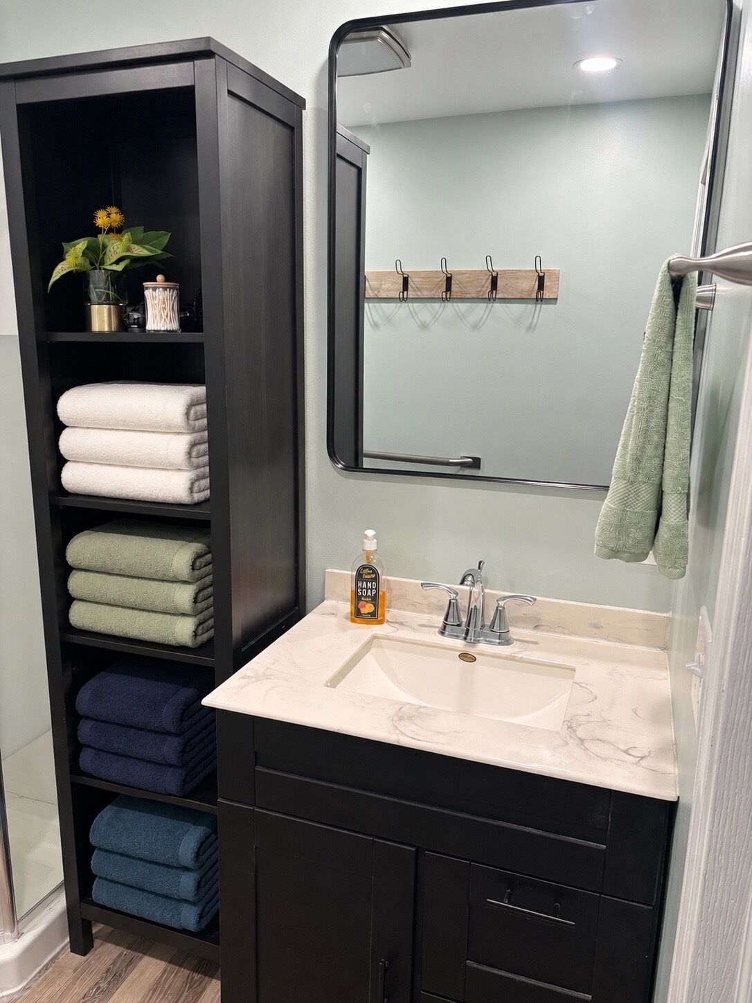 A bathroom with a dark wooden vanity, a white sink, and a mirror above it.