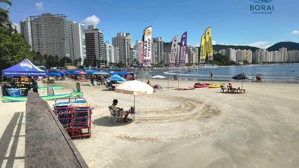 Una playa con un paseo de madera, sombrillas y sillas.