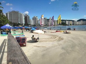 Ein Strand mit einer Holzpromenade, Sonnenschirmen und Liegestühlen.