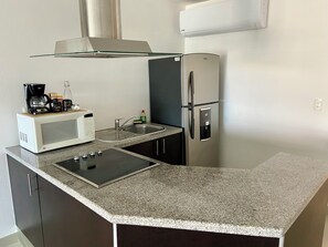 A compact kitchen with a microwave, coffee maker, sink, and stainless steel refrigerator. - Centrally located apartment with lagoon view (Cancún)