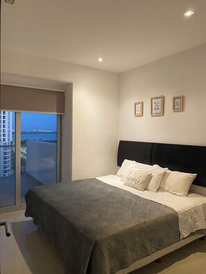 A bedroom with a bed, a view of the city, and three framed pictures on the wall. - Centrally located apartment with lagoon view (Cancún)