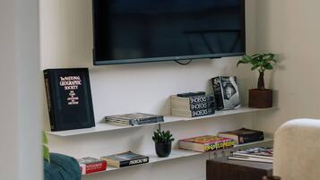 A living room with a flat-screen TV mounted on the wall, surrounded by bookshelves with various books and decorative items.