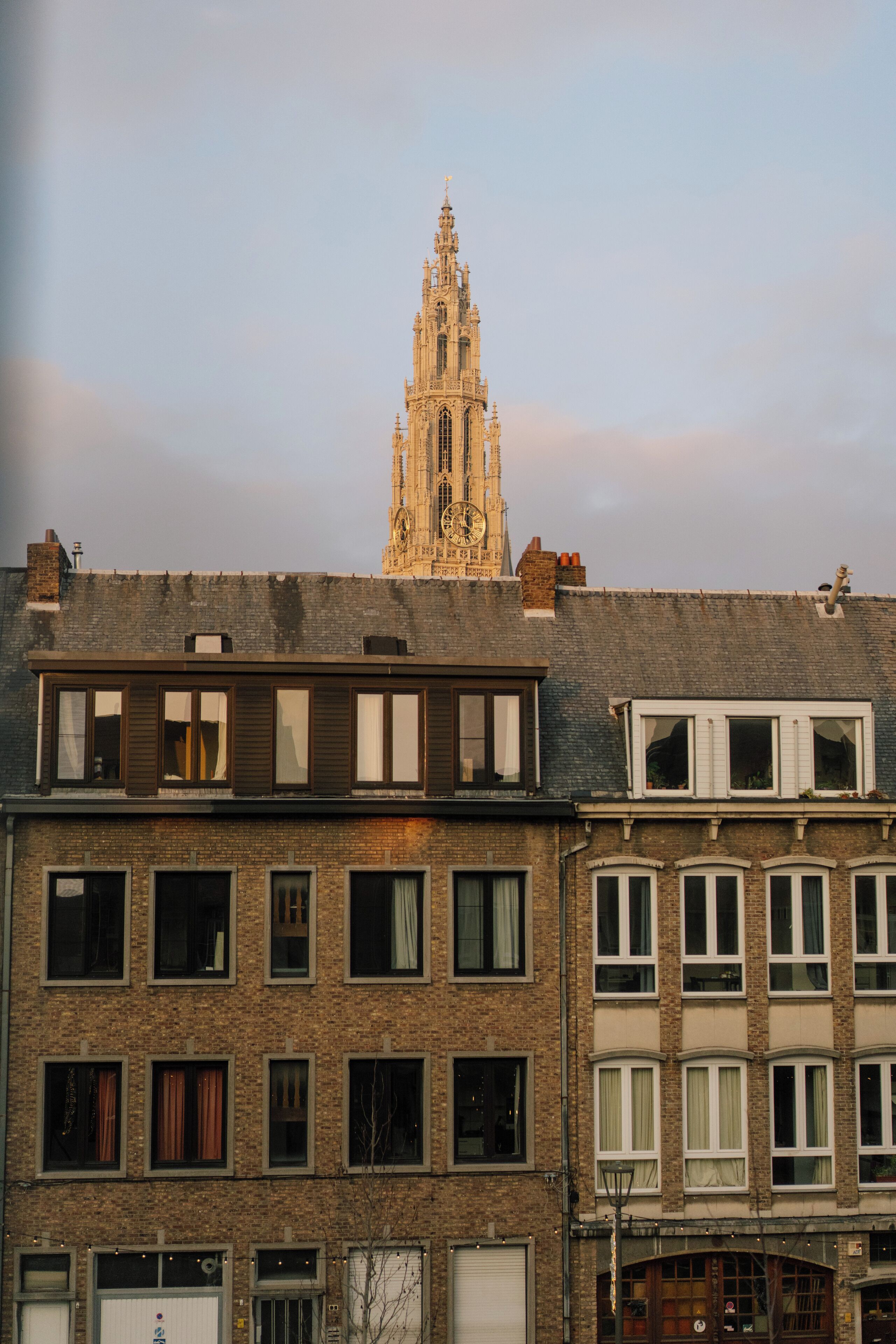 Un immeuble à plusieurs étages, avec un beffroi imposant en arrière-plan.