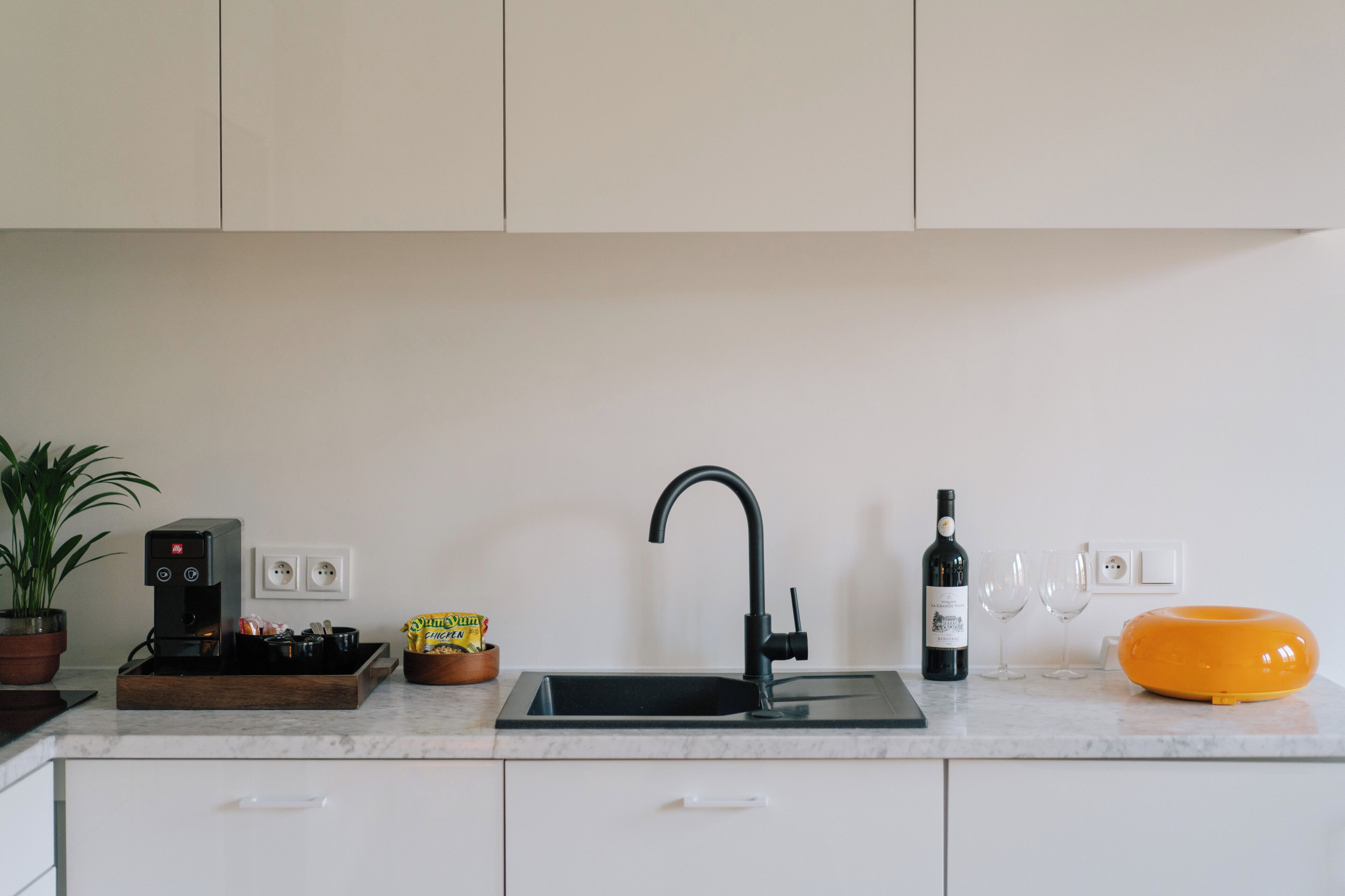 Een keuken met een koffieapparaat, een fles wijn en een schaal chips.