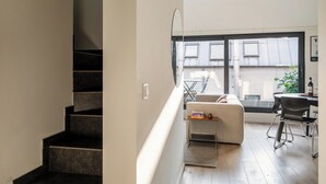 Een modern appartement met een trap, een eethoek met een tafel en stoelen, en een groot raam met uitzicht.