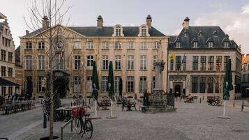 Een geplaveid plein met historische gebouwen, terrasjes en fietsen.