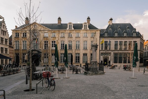Una plaza adoquinada con edificios históricos, mesas al aire libre y bicicletas.