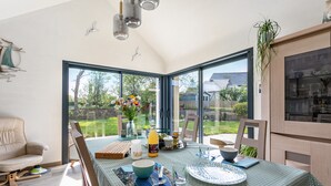 Ein Essbereich mit Tisch für zwei Personen, einer Couch und Blick ins Freie.