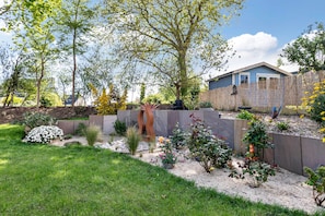 A residential backyard with a wooden fence, a variety of plants, and a blue house. - Seaside Guest Room – Beach 500m Away (Binic-Étables-sur-Mer)