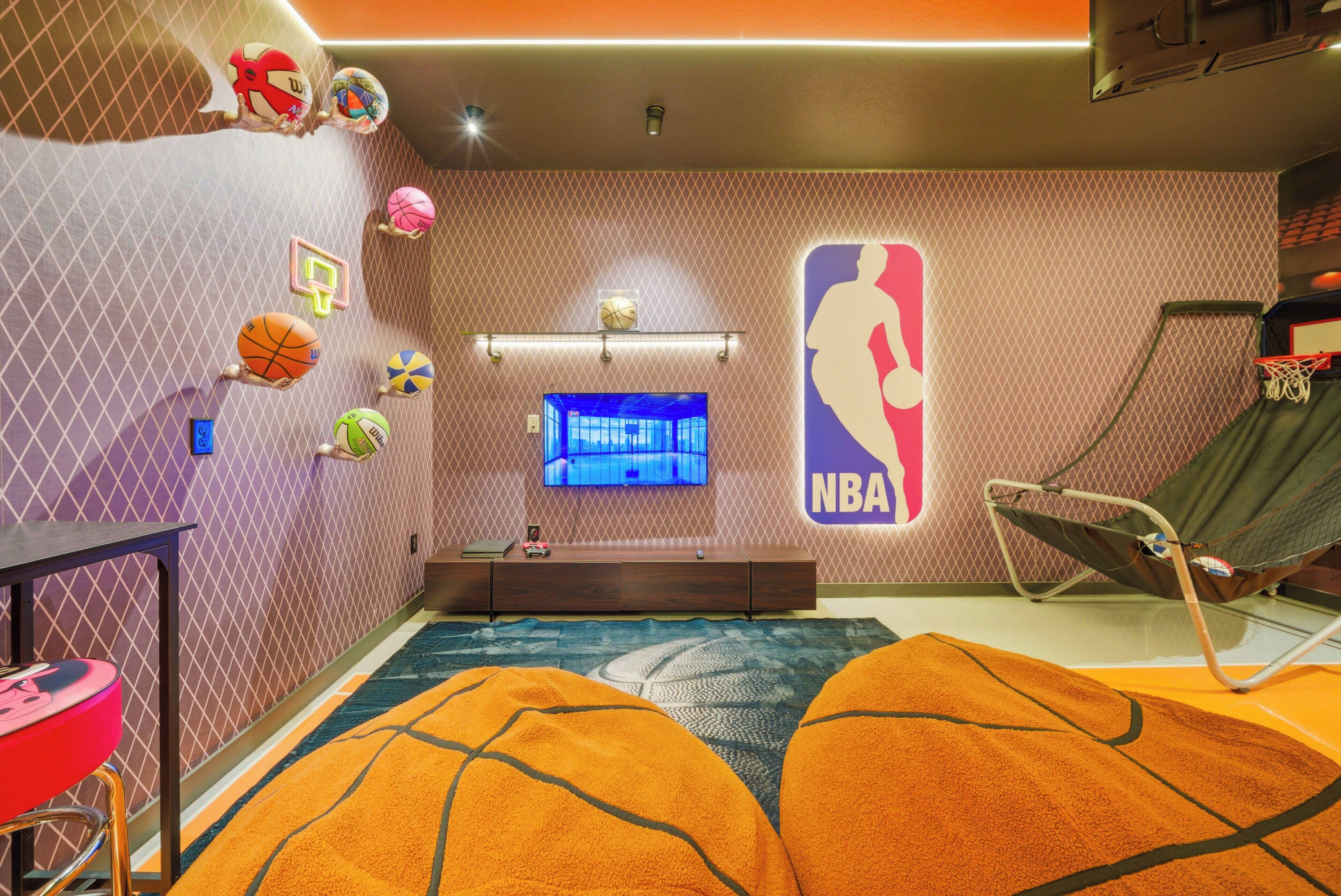 Una camera a tema basket con televisore, palloni da basket appesi alle pareti e vista su un campo da basket.