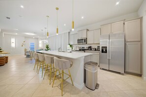 A modern kitchen with a central island, stainless steel appliances, and pendant lighting. - 5BR house at Windsor Cay Resort (Clermont)