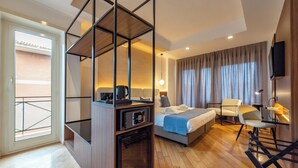 Ein Hotelzimmer mit Bett, Schreibtisch mit Computer, Stuhl, Fernseher und Balkon.
