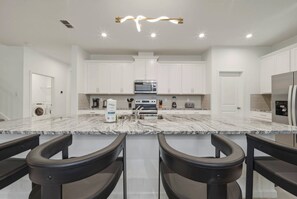 A modern kitchen with white cabinets, a granite countertop, and a stainless steel refrigerator. - 9BR house sleeps 26 with spa in kissimmee (Kissimmee)