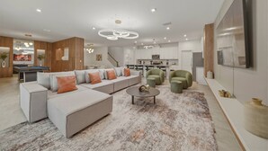 A modern living room with a sectional sofa, a coffee table, and a green armchair. - 9BR house sleeps 26 with spa in kissimmee (Kissimmee)