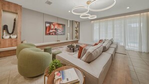 A modern living room with a sofa, green armchair, and a coffee table. There is a painting on the wall and a pendant light fixture above the seating area. - 9BR house sleeps 26 with spa in kissimmee (Kissimmee)