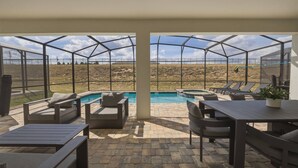 A covered outdoor area with a pool, seating, and a view of a dry landscape. - 9BR house sleeps 26 with spa in kissimmee (Kissimmee)
