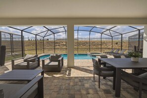 A covered outdoor area with a pool, seating, and a view of a dry landscape. - 9BR house sleeps 26 with spa in kissimmee (Kissimmee)