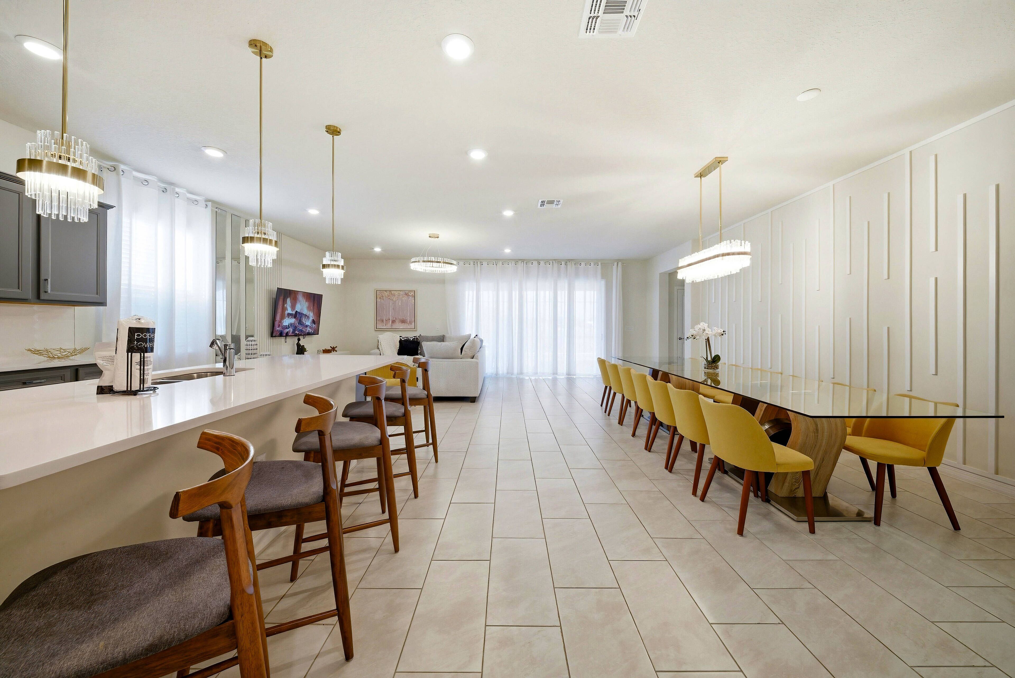 Eine moderne Küche mit Barbereich, hölzernen Barhocker und einem Esstisch mit gelben Stühlen.