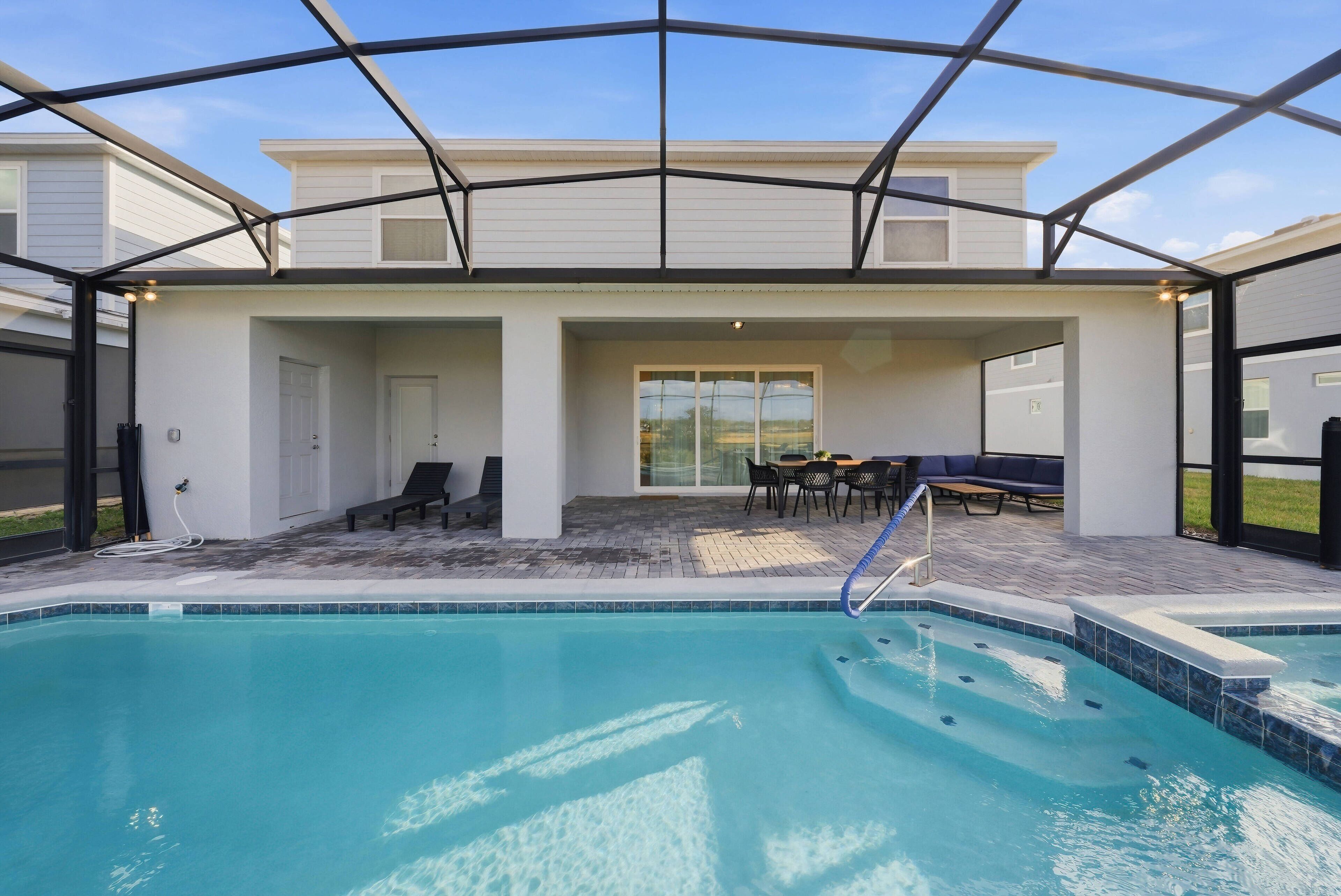 Una piscina cubierta al aire libre con zona de patio, asientos y vistas del paisaje circundante.