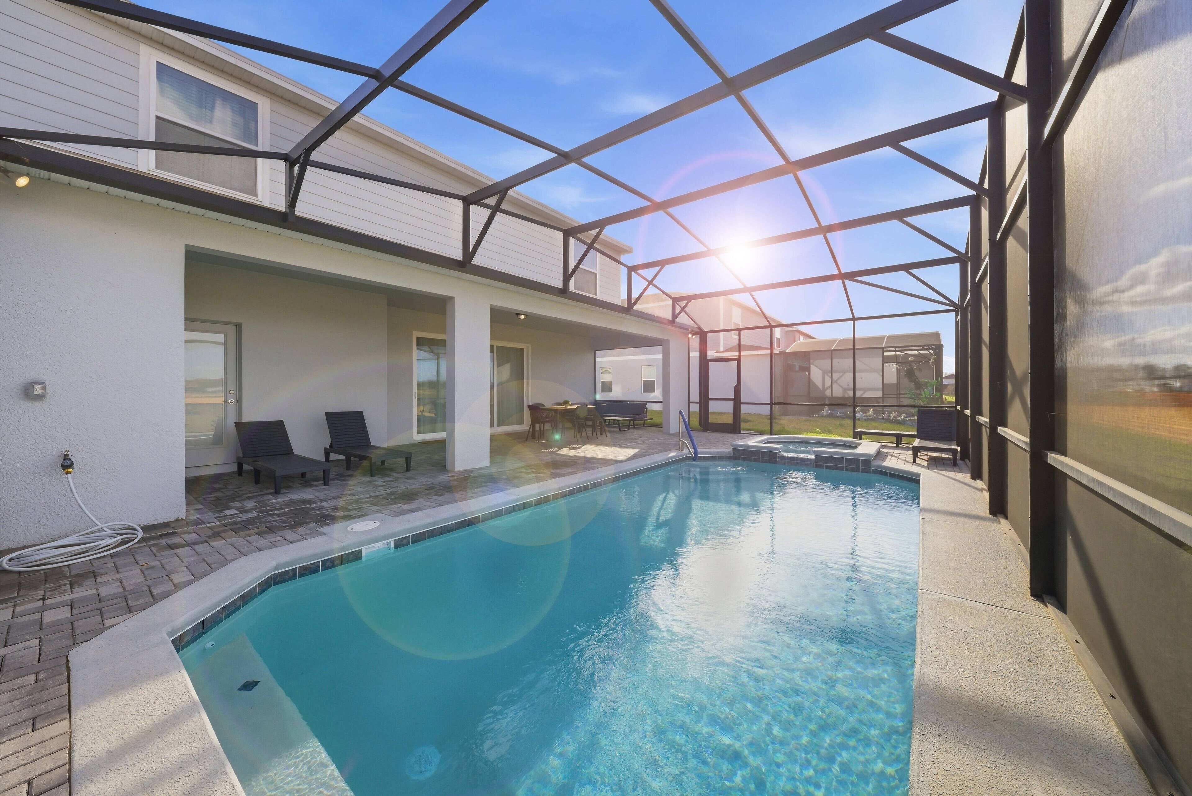 A swimming pool with a glass ceiling, surrounded by lounge chairs and a patio area.