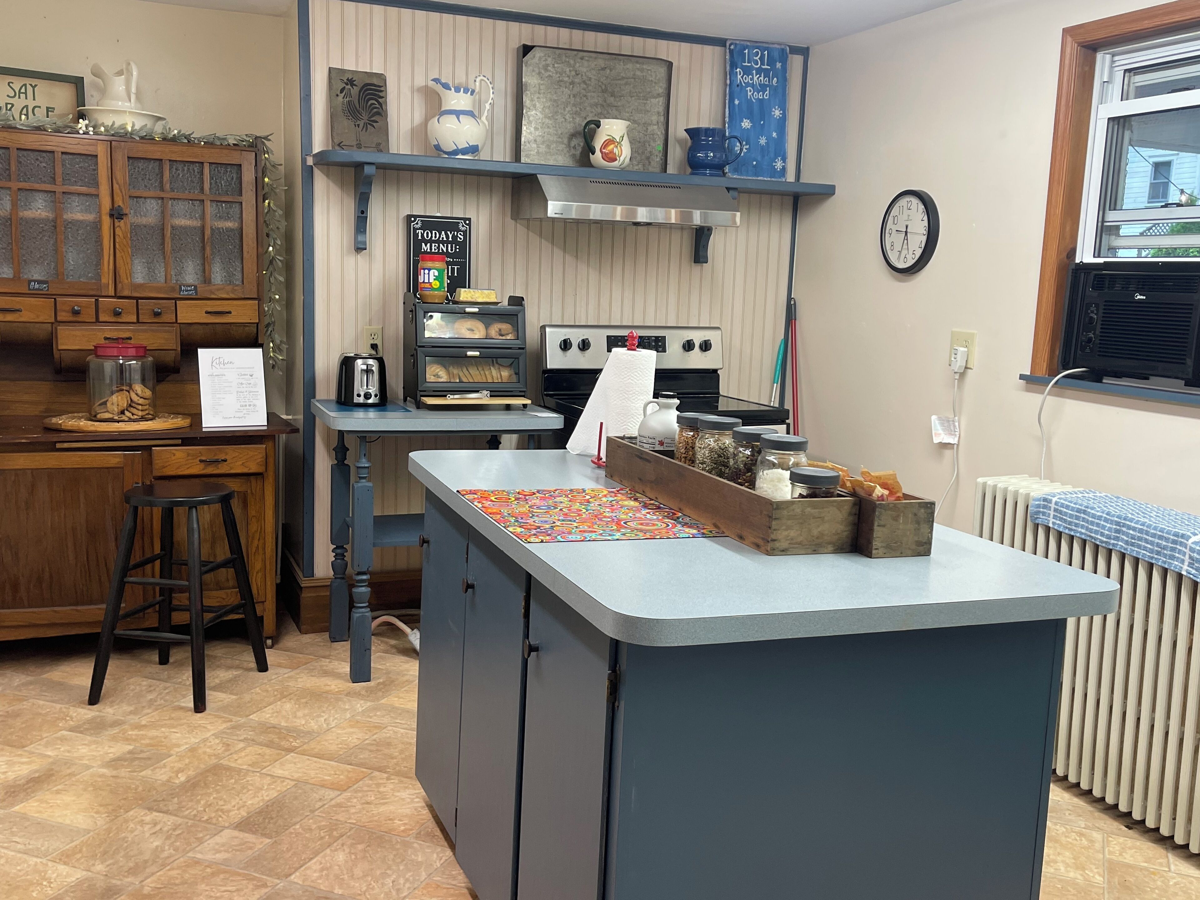 A kitchen with a central island, a stove, a toaster, and a sign indicating a menu.