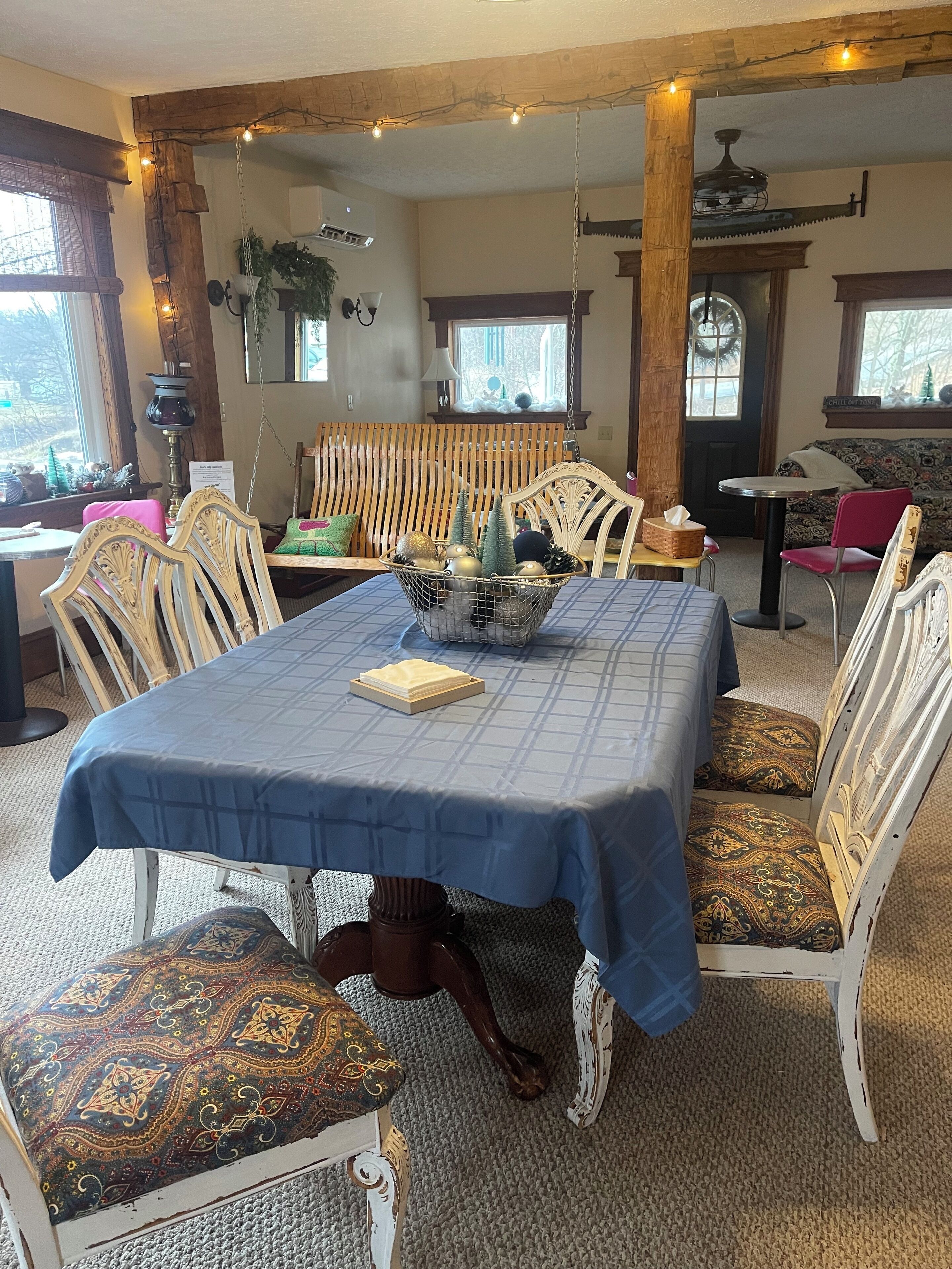 A dining area with a blue tablecloth, white chairs, and a decorative centerpiece.