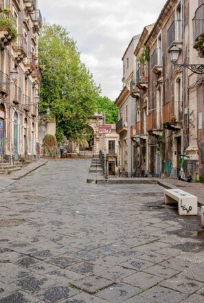 Una calle empedrada bordeada de edificios históricos, un banco y una moto.