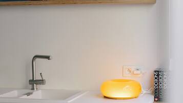 A bathroom with a wooden vanity, a modern faucet, and a shelf with framed pictures and a plant.