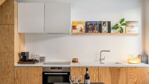 A modern kitchen with a wooden cabinet, a coffee machine, a sink, and a wine bottle on the counter. - A Place - Leeuwenstraat 15 (Antwerp)
