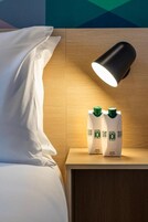 Ein Hotelzimmer mit einem Bett, einem Nachttisch, einer Lampe und zwei Flaschen Hotel 101.