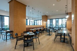 A modern dining area with wooden paneling, black chairs, and tables arranged for groups. - Hotel101- Madrid (Madrid)