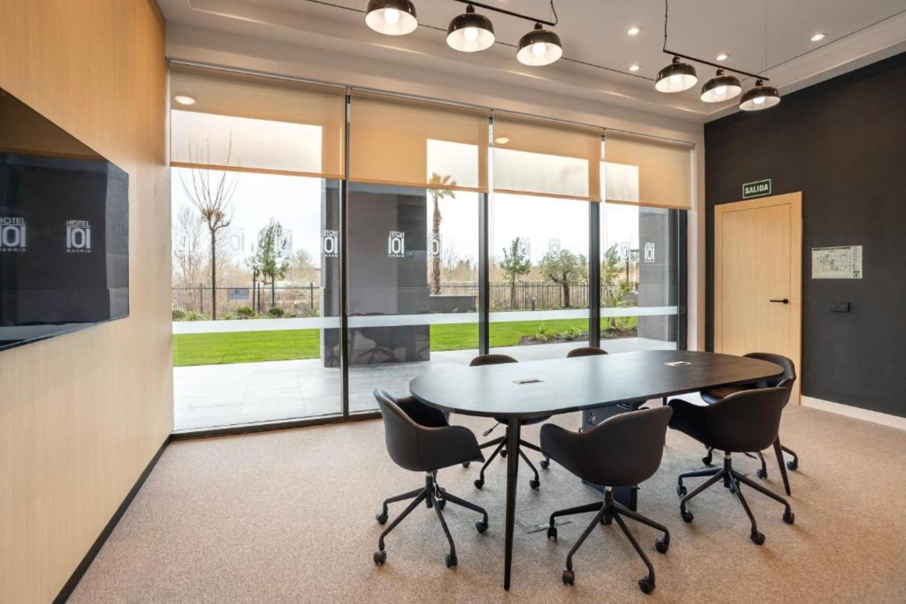 A conference room with a large table, four chairs, and a door labeled 'SALIDA'.