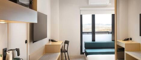Habitación de hotel con cama, escritorio, silla, televisor y ventana con vistas.