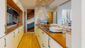 A modern kitchen with wooden countertops, white cabinets, and a patterned backsplash.