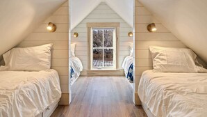 Un dormitorio con dos camas, una ventana y paredes de madera.