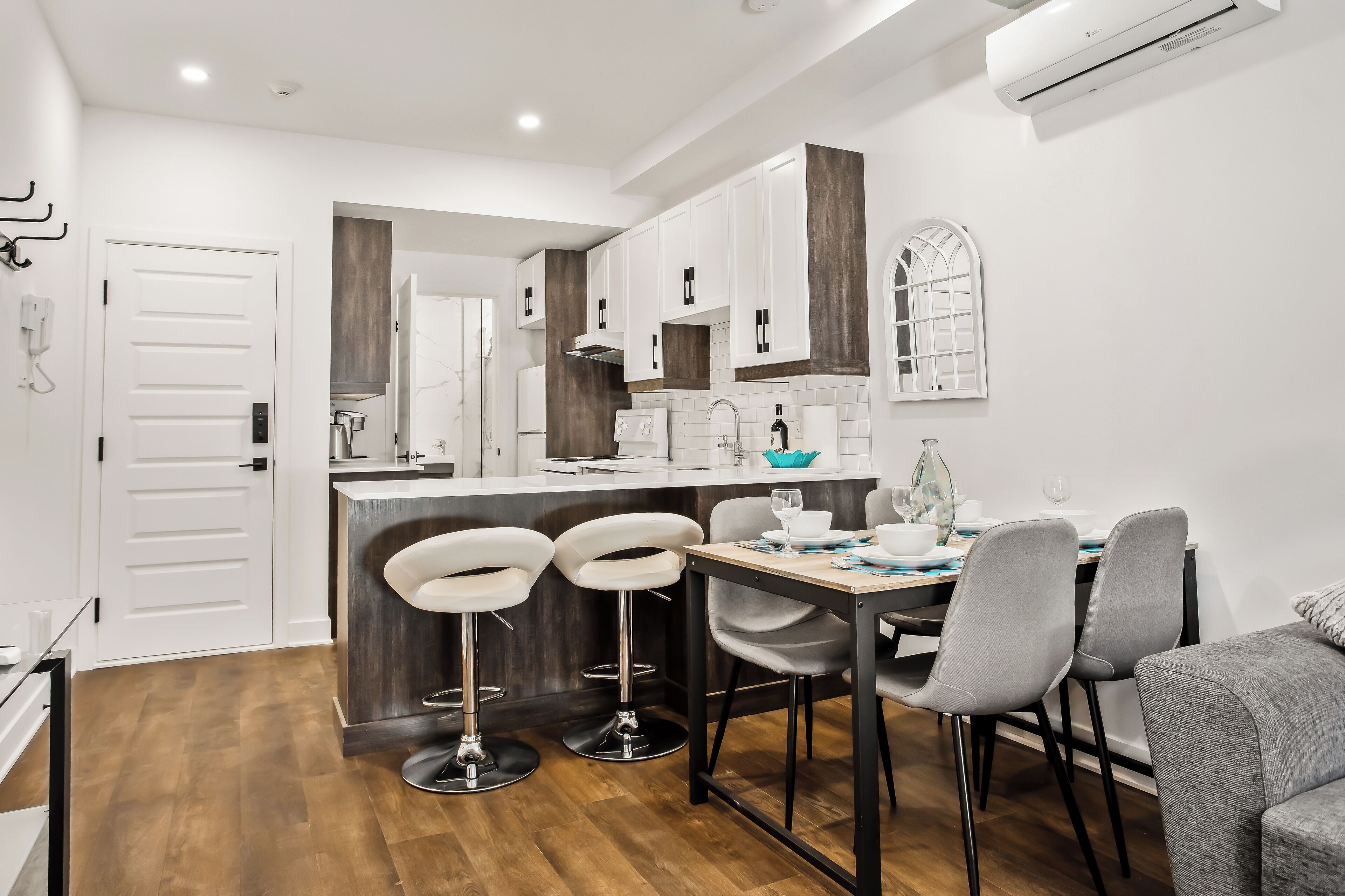 A modern kitchen with white cabinets, a wooden countertop, and a dining area with grey chairs and a wooden table.