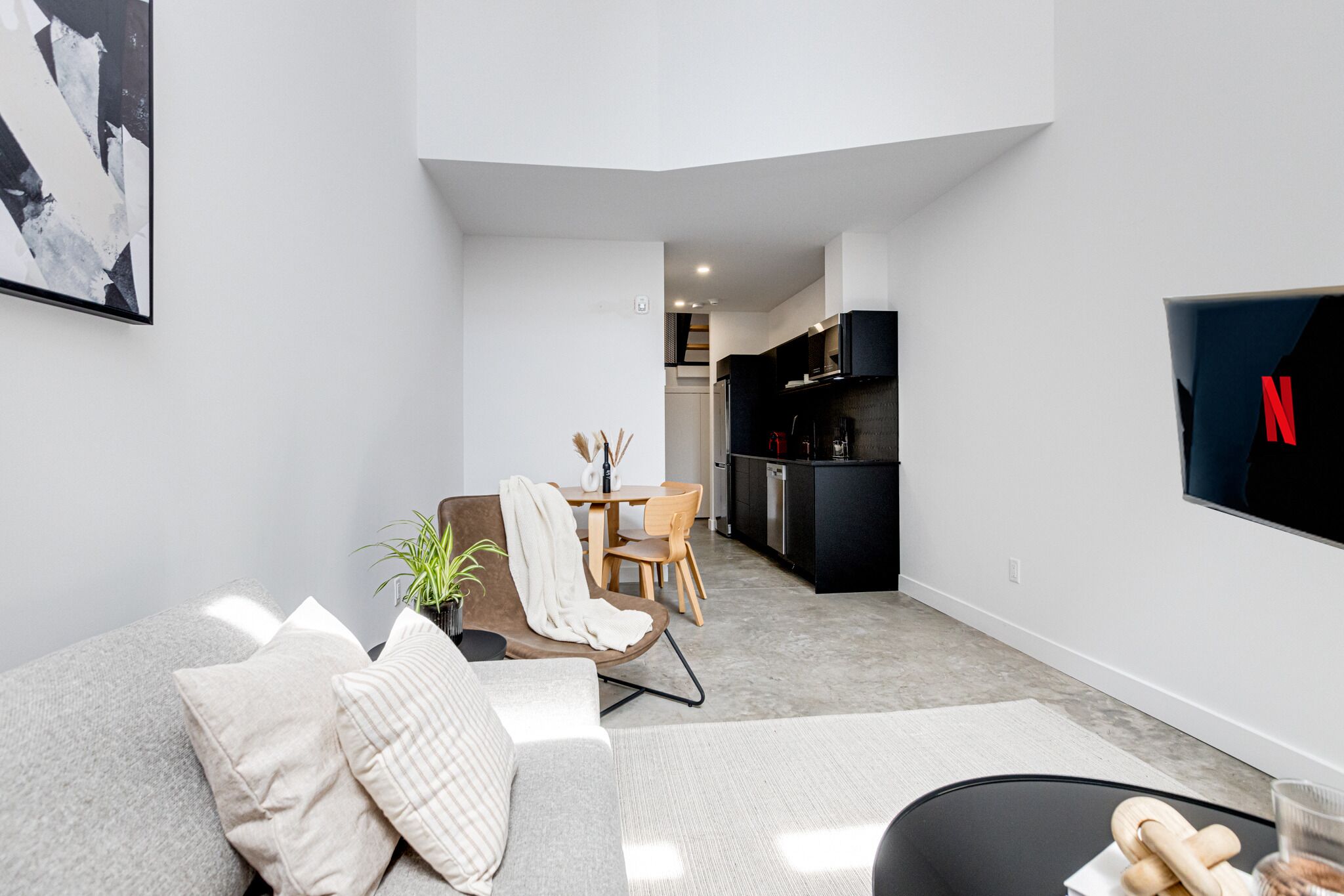 A modern living room with a grey sofa, a coffee table, and a TV mounted on the wall.