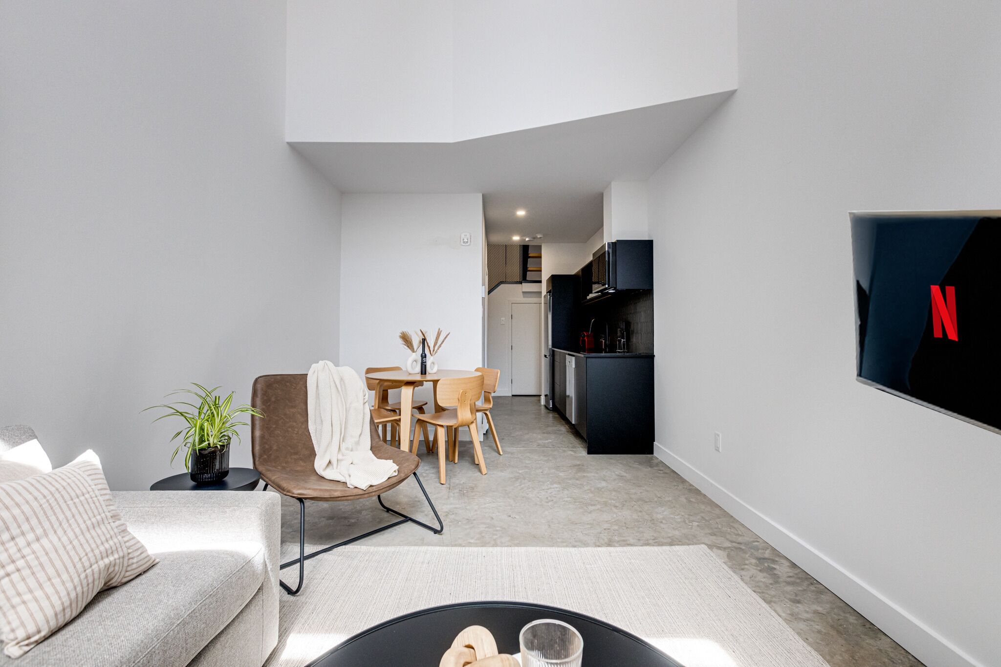 Un salon moderne comprenant un canapé, une table basse et un coin repas avec des chaises et une table.