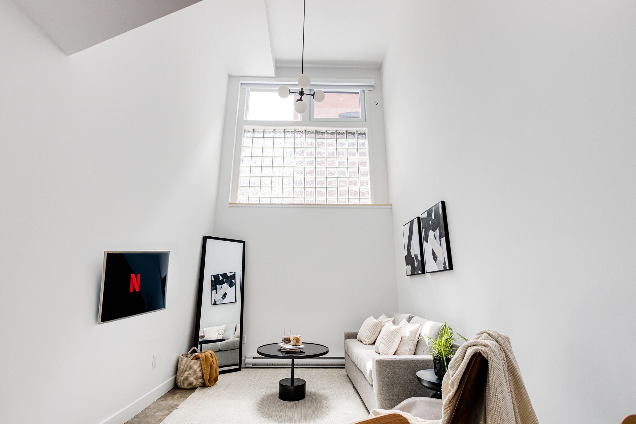 Una sala de estar moderna con un sofá, una mesa de centro, un televisor y obras de arte en las paredes.