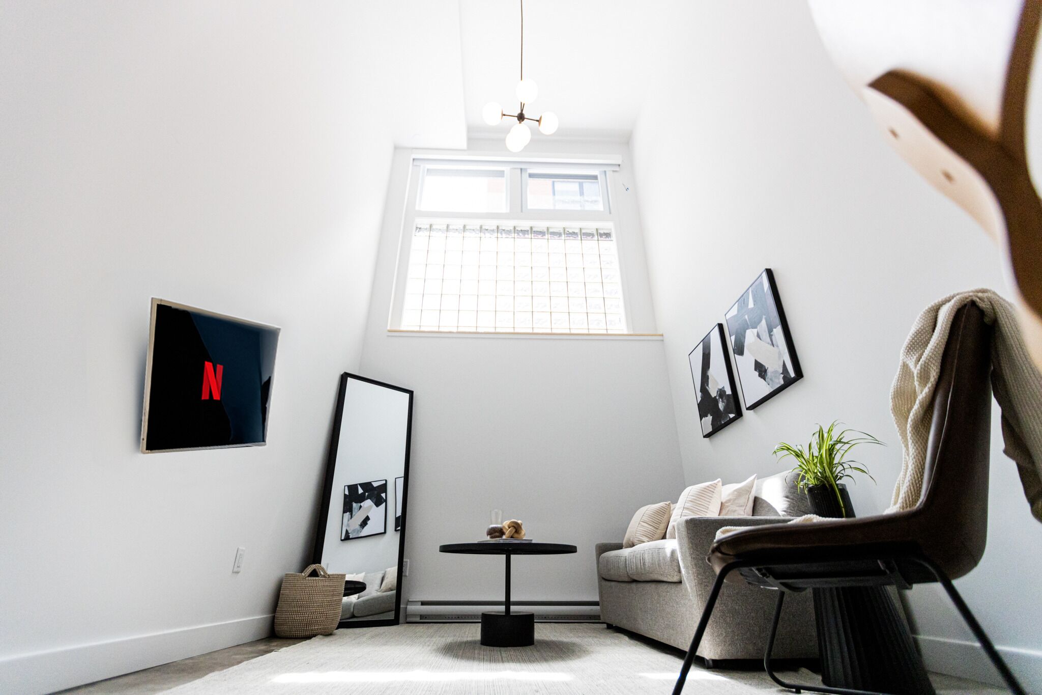 A modern living room with a large window, a round table, a sofa, and a chair.