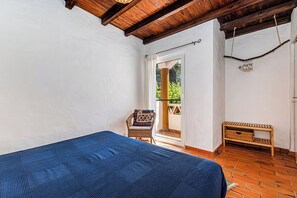 Une chambre à coucher avec un lit, une chaise, une petite table et une vue sur l’extérieur.