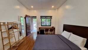 Une chambre à coucher avec un lit, un bureau et une chaise. On y trouve une échelle en bois et une fenêtre donnant sur l’extérieur.