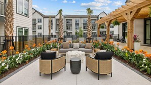A courtyard with outdoor seating, palm trees, and a pergola. - Global Luxury Suites Downtown Charleston (North Charleston)