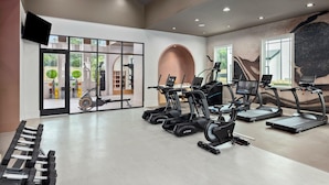 A modern gym with treadmills, a weight bench, and exercise equipment. - Global Luxury Suites Downtown Charleston (North Charleston)