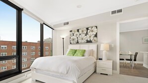 A modern hotel room with a large bed, a bedside table, a desk, and a chair. - Global Luxury Suites Downtown Charleston (North Charleston)