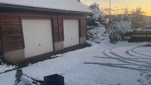 A building with a snow-covered roof and a garage door. There are snow-covered bushes and a paved driveway with visible tire tracks. - Large family home with extensive grounds (Tortebesse)