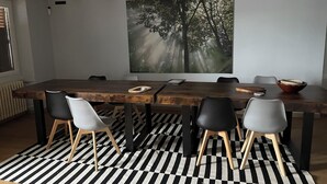 A modern dining area with a large wooden table, black and white striped rug, and a forest-themed wall art. - Large family home with extensive grounds (Tortebesse)