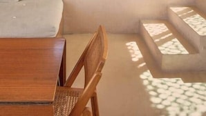Ein Schlafzimmer mit einem großen Bett, einem Holzstuhl, einem Tisch und einer kleinen Lampe.